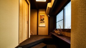 Un pasillo estrecho con escaleras de madera, una obra de arte enmarcada en la pared y una ventana con vistas.