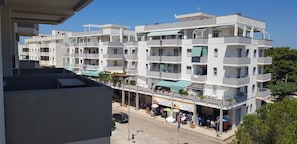 A multi-story residential building with balconies, a ground-level shop, and a clear blue sky. - Appartamenti Rivabella Gallipoli (Gallipoli)