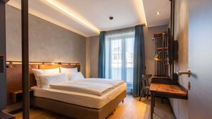 Habitación de hotel moderna con una cama grande, un escritorio y vistas a la ciudad.
