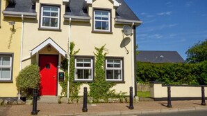 Ein zweistöckiges Haus mit roter Tür, Satellitenschüssel und Satellitenfernsehen.