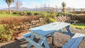 A picnic table set in a natural landscape with a view of mountains and a body of water. - Kate's Cottage (Valentia Island)