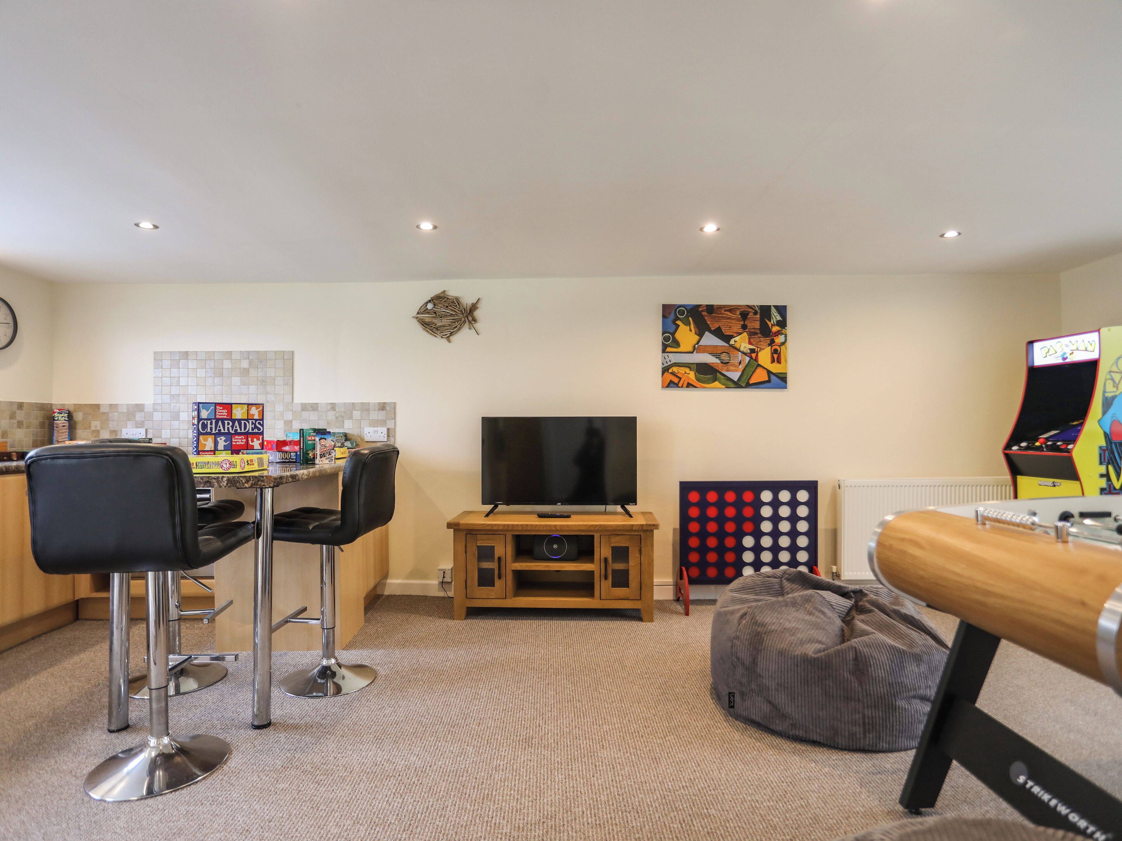 A modern living room with a flat-screen TV, a gaming console, and a bean bag chair.