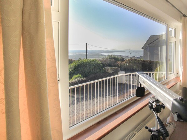 A balcony with a view of the sea, a railing, and a telescope.