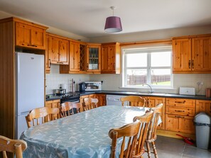A kitchen with wooden cabinets, a refrigerator, a stove, a microwave, and a dining table with chairs. - Doornogue (Templetown)