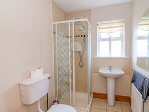 A bathroom with a toilet, a glass-enclosed shower, a sink, and a window. - Doornogue (Templetown)