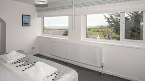Ein Schlafzimmer mit großem Fenster, Heizkörper und einem Bett mit aufgerollten Handtüchern.