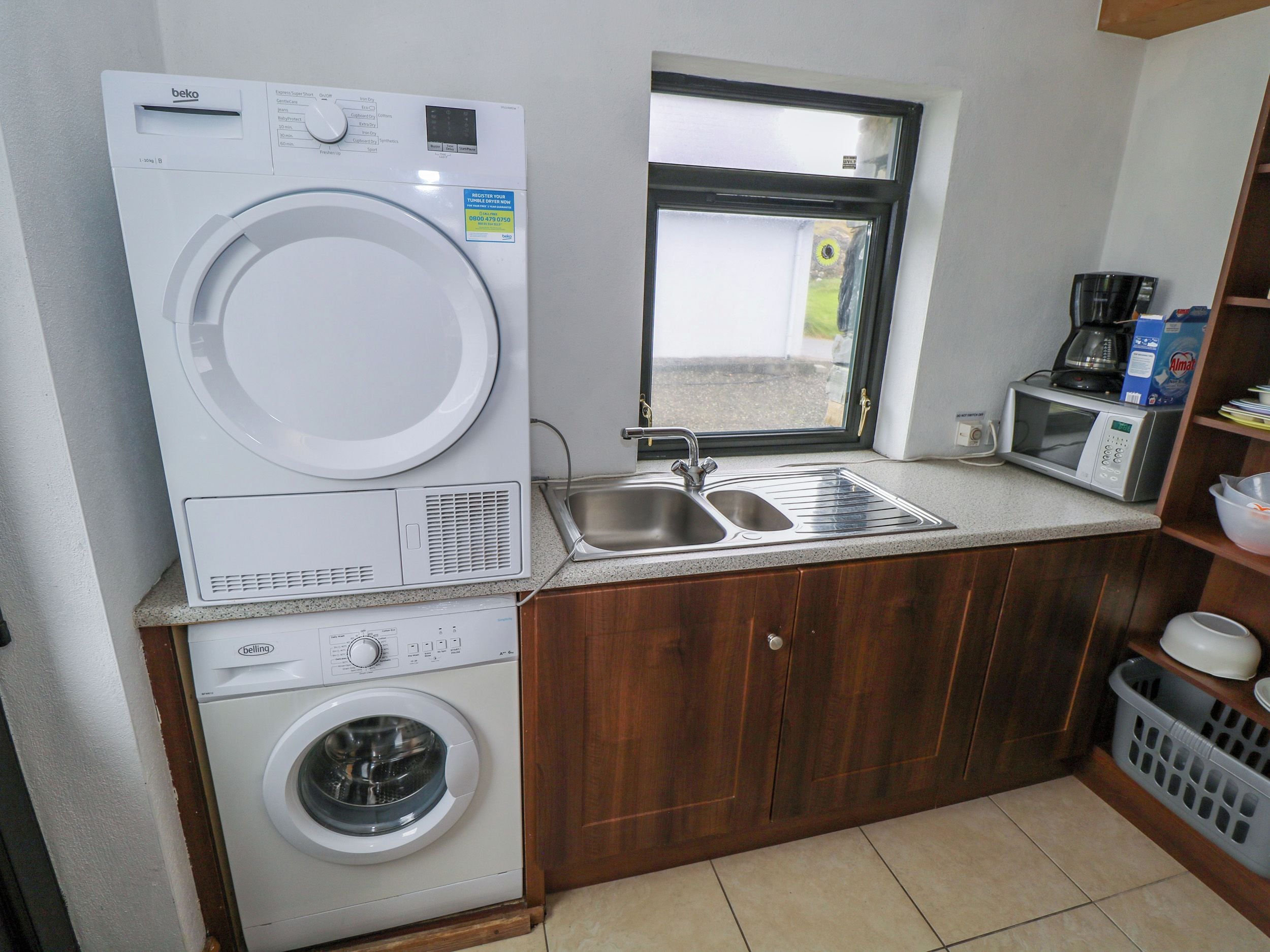 Una cocina compacta con lavadora, microondas y fregadero.