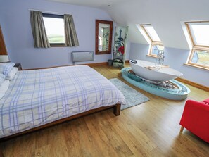Quarto com cama, banheira e uma cadeira vermelha.