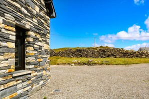 A stone building with a gravel driveway and a stone wall in the background. - Ocean Sail House (Maghery)
