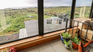 A balcony with a view of a grassy landscape and a stone wall. - Ocean Sail House (Maghery)