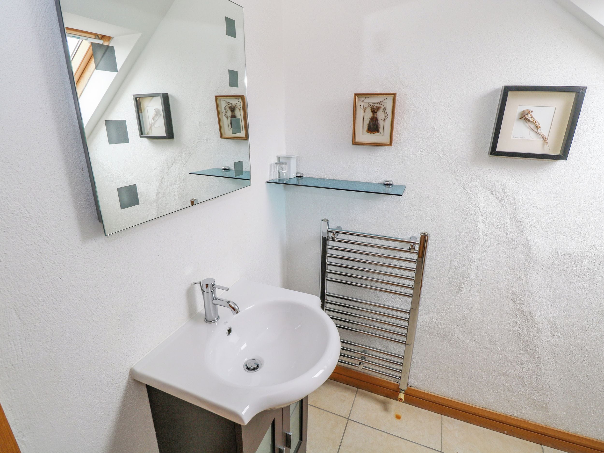 Une salle de bain avec un lavabo blanc, un miroir et un porte-serviettes.