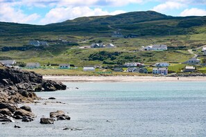 A coastal village with houses on a hillside, a rocky shoreline, and a clear view of the sea. - Ocean Sail House (Maghery)