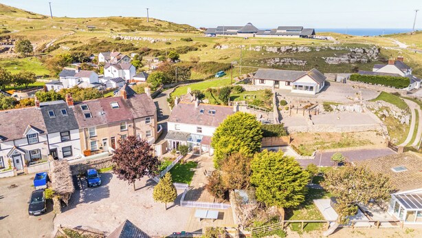 Un village côtier doté de maisons traditionnelles en pierre, d’une plage de sable et offrant une vue dégagée sur la mer.
