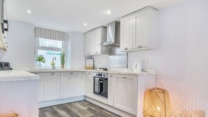 Una cocina moderna con armarios blancos, horno empotrado y un amplio ventanal.