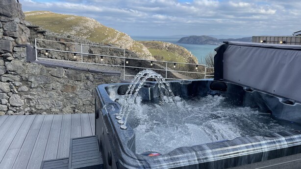 Un jacuzzi con agua corriente, frente a colinas rocosas y un cielo despejado.