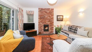 A living room with a brick fireplace, a television, and a sofa. - Casalmare (Exmouth)