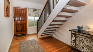 A wooden staircase with a handrail, a door with a window, and a rug on the floor. - Casalmare (Exmouth)