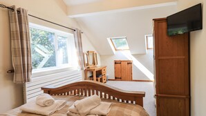 Quarto com cama de madeira, guarda-roupa de madeira e televisão na parede.