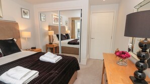 A hotel room with a bed, a desk, a lamp, a vase with flowers, and a mirror. - 42 Dart Marina (Dartmouth)