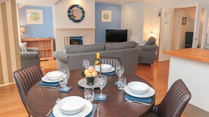 A dining area with a round table set for four, surrounded by leather chairs. A fireplace is visible in the background, and a television is mounted on the wall. - 42 Dart Marina (Dartmouth)