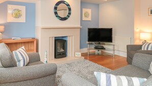 A modern living room with grey sofas, a flat-screen TV, a fireplace, and decorative wall art. - 42 Dart Marina (Dartmouth)