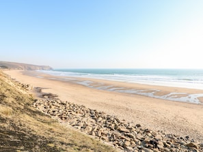 A coastal beach with rocky terrain and a clear view of the ocean. - Ocean Blue (Penzance)