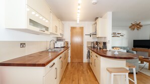 Una cocina moderna con encimeras de madera, armarios blancos y una isla central con taburetes.