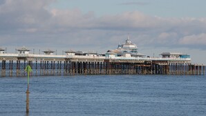 A pier with a large building at the end, featuring multiple levels and a dome structure.