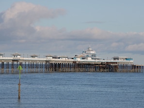 A pier with a large building at the end, featuring multiple levels and a dome structure.