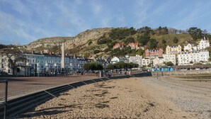 A coastal town with a prominent monument, historic buildings, and a rocky hillside in the background.