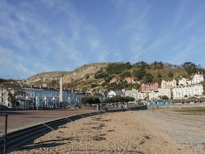 A coastal town with a prominent monument, historic buildings, and a rocky hillside in the background.