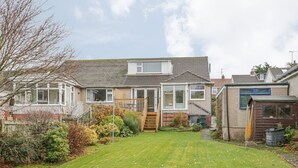 A residential house with a front yard, a wooden staircase, and a small garden area.