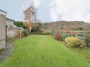 A well-maintained grassy yard with a brick wall and a wooden fence.