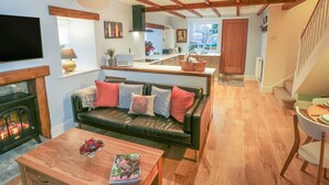 A cozy living room with a fireplace, a wooden coffee table, and a leather sofa with cushions. - May Cottage (Scarborough)