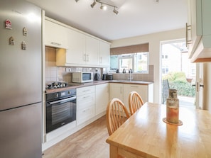 A modern kitchen with white cabinets, a stove, microwave, and a dining table with chairs.