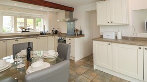 Een moderne keuken met witte kasten, een groot eiland en een eethoek met een glazen tafel.