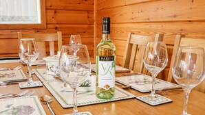 Una mesa de madera con copas de vino, una botella y vajilla floral.