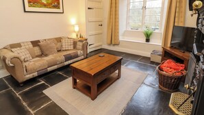 A cozy living room with a sofa, a wooden coffee table, a television, and a fireplace.