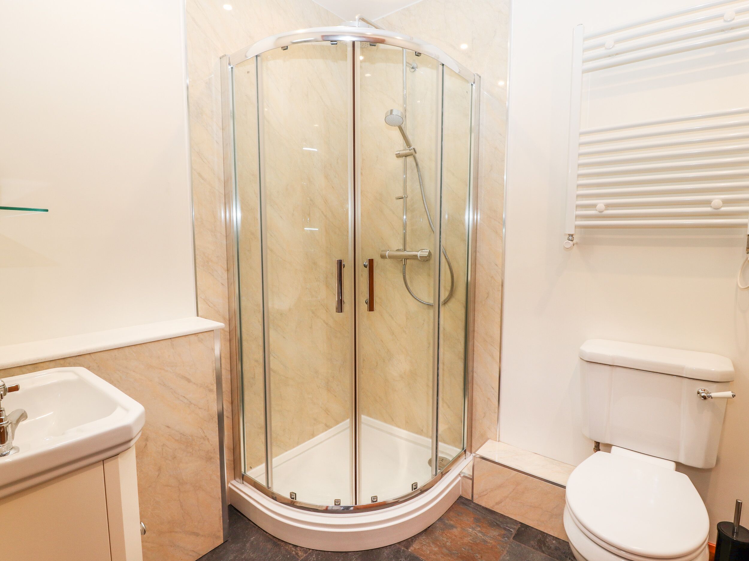 Ein modernes Badezimmer mit einer gläsernen Duschkabine, einer weißen Toilette und einem Waschbecken.