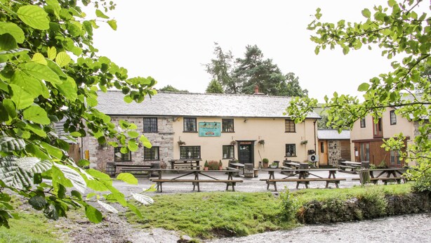 A stone building with a sign reading "Open All Hours" and outdoor seating. - Stiperstones View (Shrewsbury)