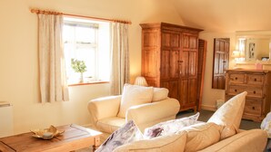 A cozy living room with a sofa, a wooden cabinet, and a small table. - Stiperstones View (Shrewsbury)