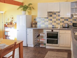 A compact kitchen with white cabinets, a Bosch oven, a microwave, and a tiled backsplash. - Cranberry Cottage (Shrewsbury)