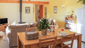 A cozy living room with a fireplace, sofa, and dining table. - Cranberry Cottage (Shrewsbury)