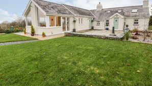 A two-story house with a large patio and a well-maintained lawn. - Tŷ'n Lôn Bach (Caernarfon)