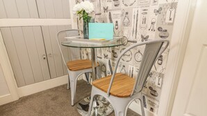 A small dining area with a round glass table and two chairs with wooden seats and metal frames. - Bank End Cottage (Carnforth)