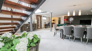 A modern living space with a staircase, dining area, and a motorcycle.