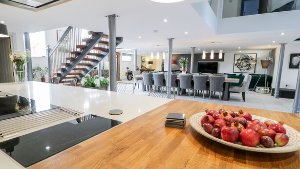 A spacious living area with a central island, a staircase, and a dining area with modern furniture.