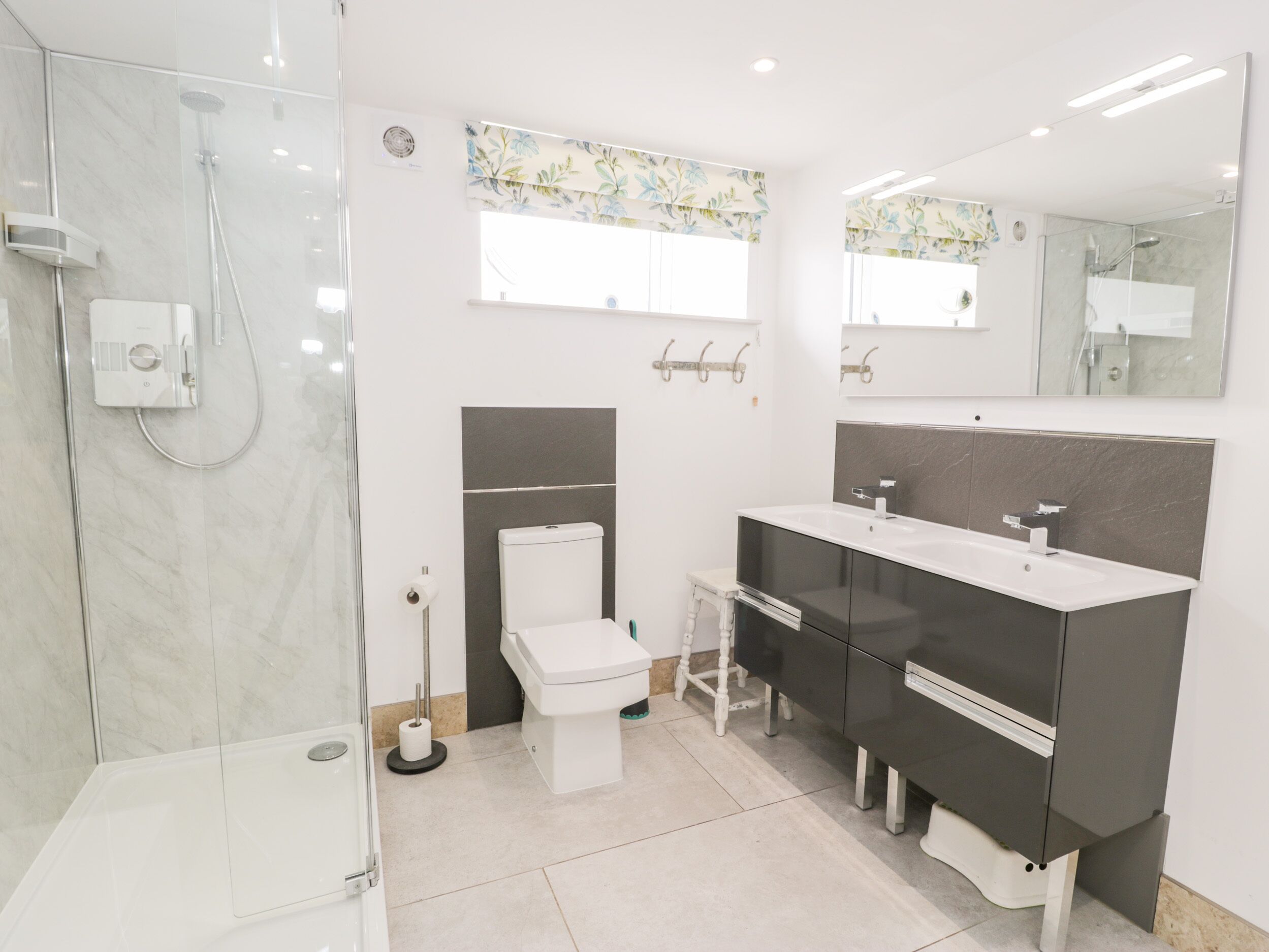 Une salle de bain moderne avec une douche à parois de verre, des toilettes, un meuble-lavabo avec un miroir et un porte-serviettes.