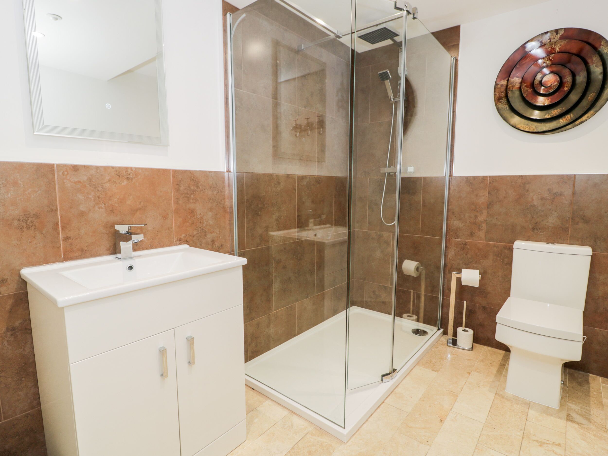 Un baño moderno con ducha acristalada, lavabo blanco y retrete.