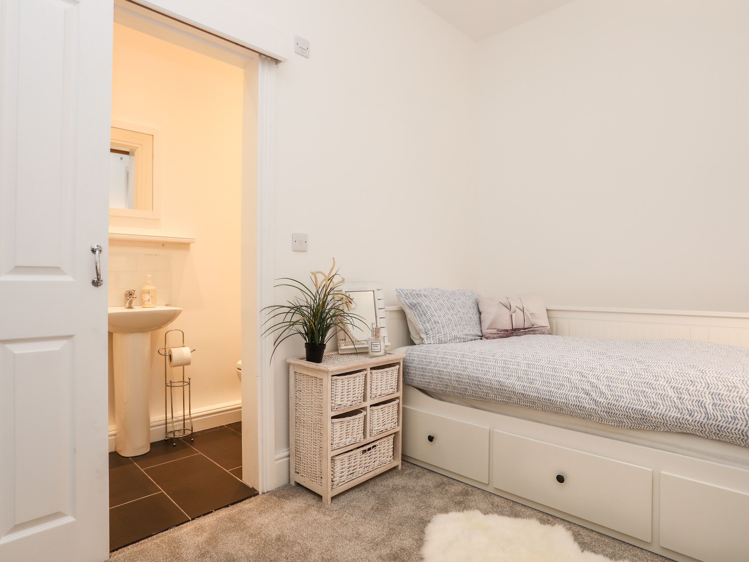 A bedroom with a bed, bedside table, and a small white cabinet.